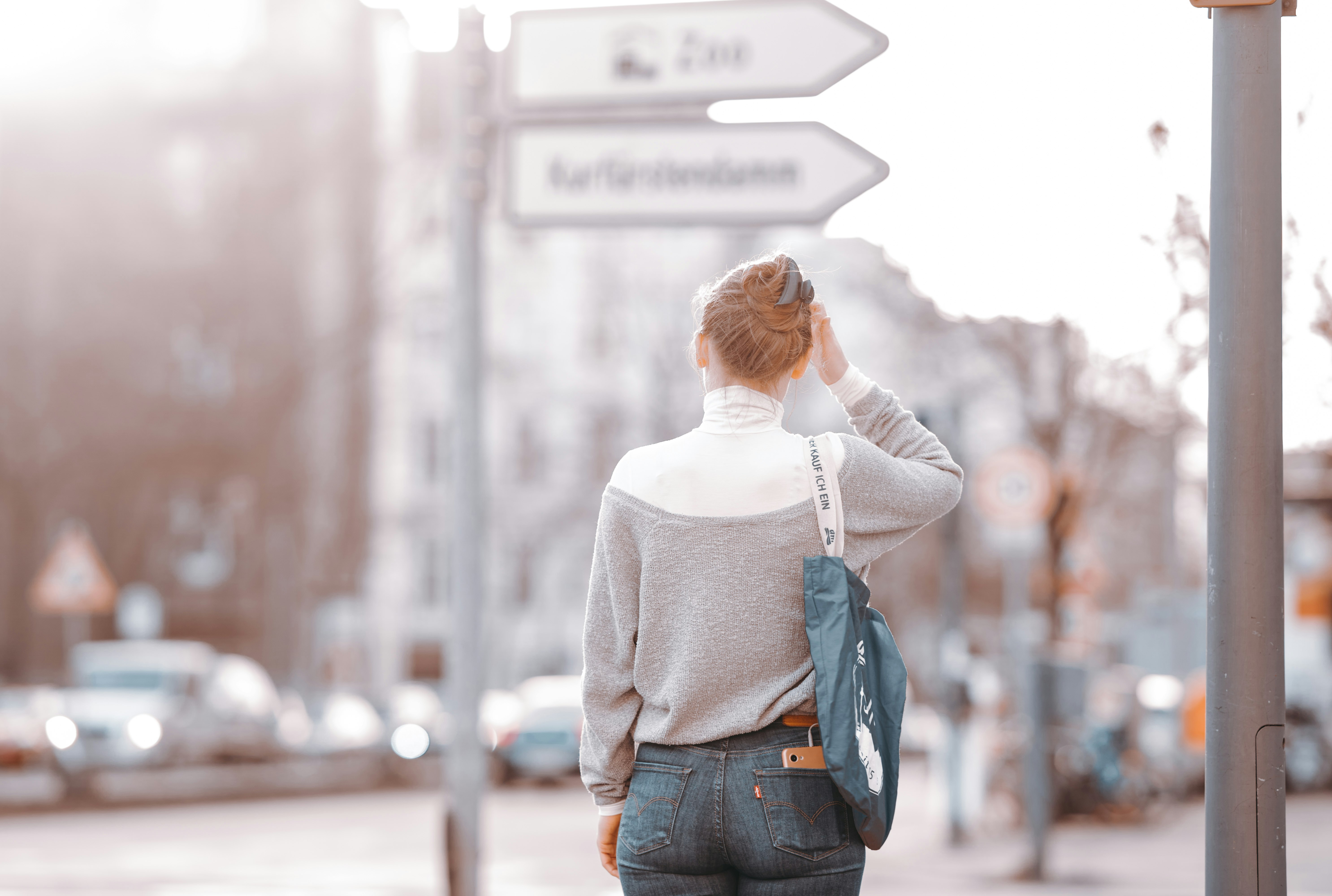 woman in white long sleeve shirt and blue denim jeans standing on sidewalk during daytime